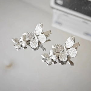 Detail of silver butterfly hair clips with intricate metal textures and reflective finish