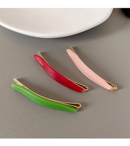 Detailed view of curved faux leather hair clips in green, red, and pink on a white plate