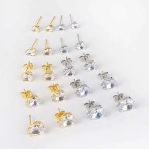 Flat lay of gold and silver heart zircon stud earrings in various sizes on white