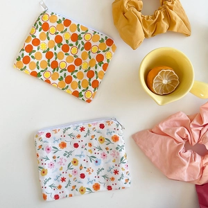 Flat lay of small floral cotton pouches with citrus prints and white zipper detail