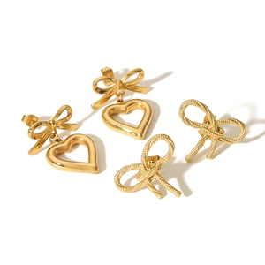 Boucles d'oreilles nœuds dorés et cœurs évidés avec texture tressée sur fond blanc pur