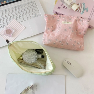Detailed view of floral jacquard pouches showing spacious interior for cosmetics and brushes