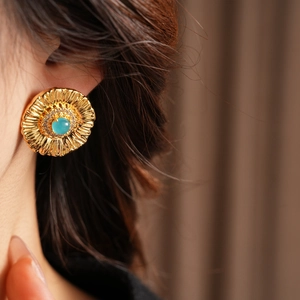 Detailed close-up of golden sunflower earrings with turquoise stone and zircon accents