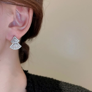 Detail shot of shimmering zircon encrusted geometric fan-shaped earrings on model ear