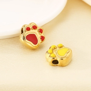 Macro shot of gold stainless steel paw beads with red and yellow enamel details