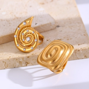 Close-up of gold spiral and rectangular rings with matte finish on stone base
