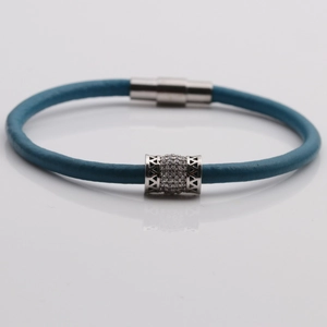 Dettaglio del bracciale in pelle intrecciata blu con perla in zircone e chiusura magnetica