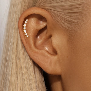 Detail of gold ear crawler featuring round and teardrop cubic zirconia on ear lobe