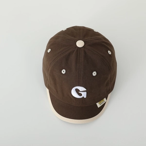 Detail of baby baseball cap with G embroidery and daisy eyelets on brown canvas