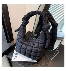 Detailed close-up of quilted black puffer cloud bag with stylish knot strap detail