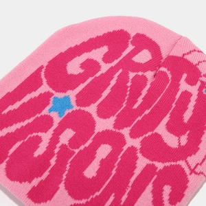 Macro view of pink knitted beanie featuring jacquard star and pixelated letter patterns