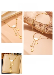 Detail of gold necklace with white cloud, moon, and star charms on a stone display