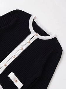 Detail of knit cardigan with contrast white trim and gold buttons in luxury style