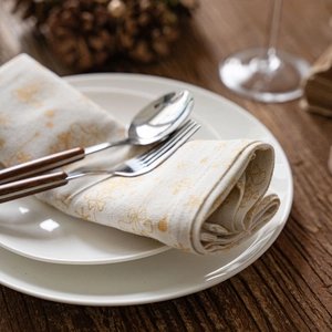Serviettes de Noël à imprimé doré sur assiette blanche et couverts à manche en bois