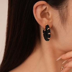 Side view detail of U-shaped leather ear studs with gold beads for women