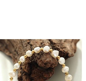 Detail of baroque pearl bracelet with gold beads on rustic wood texture background