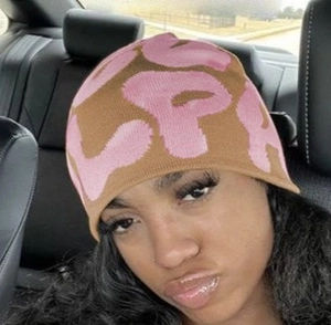 Close-up of brown and pink knit beanie with SP embroidery in car interior shot