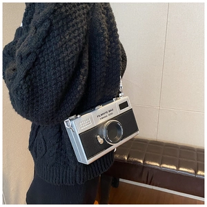 Detail showing creative silver camera-shaped handbag with adjustable shoulder strap