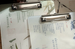 Detail of acrylic clipboards featuring Chinese calligraphy and silver metal clips