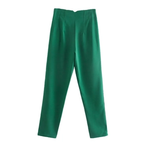 Detail of high-waisted emerald green trousers with front pleats and tapered leg design