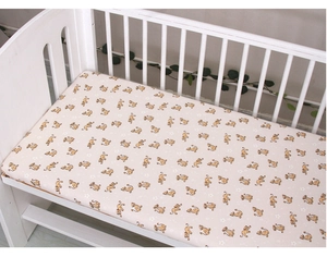 Close-up of baby crib sheet featuring a cute cartoon lion pattern on cream fabric