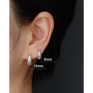 Detailed close-up of 8mm and 10mm silver spiral hoop earrings worn on ear for scale