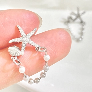 Macro shot of silver starfish ring with rhinestones, shell detail and pearl charms