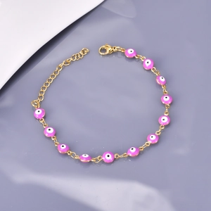 Macro view of gold stainless steel bracelet with purple Evil Eye enamel charms and lobster clasp