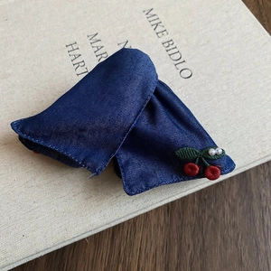 Detail of blue denim bow hair clip with embroidered cherries and white pearls