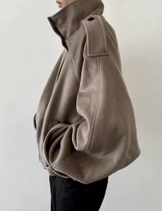 Detail view of taupe wool-like jacket featuring a stand collar and epaulet shoulder