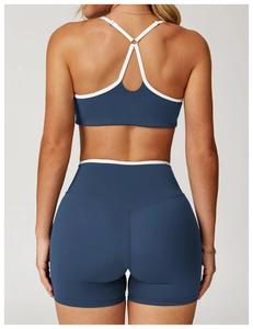 Detail van hoge taille yogaset met witte biezen op sportbeha en diepzeeblauwe korte broek