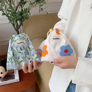 Floral canvas drawstring pouches with blue tulip patterns shown in a cozy home setting