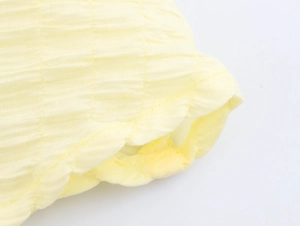 Detail shot of light yellow textured crepe fabric with fine stitching on the dress