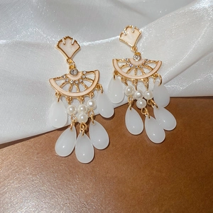 Detailed close-up of fan-shaped pearl earrings with elegant white teardrop glass tassels