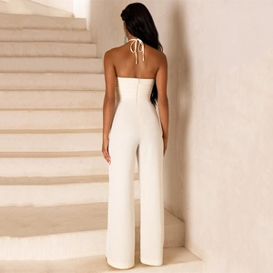 Detail view of a white backless halter jumpsuit showing the open back design on a model