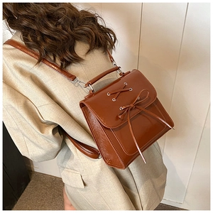 Detail of vintage caramel brown PU leather backpack with bow tie and drawstring design