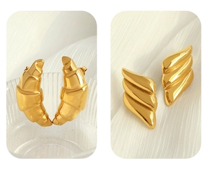 Detail of 18k gold croissant and wing earrings with textured metallic finish