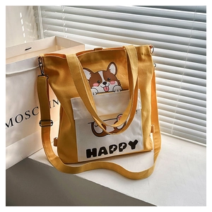 Detail view of yellow canvas tote bag with cartoon corgi print and HAPPY pocket