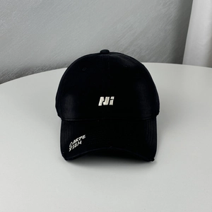Detail of white NI embroidery and Carpe Diem script on black cotton baseball cap brim