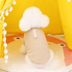 Detail of plush beige dog vest with metal D-ring for leash attachment shown on puppy