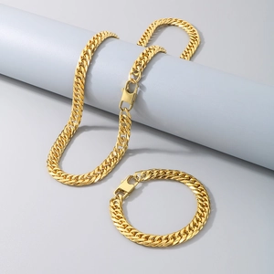 Close-up of golden stainless steel Cuban chain necklace and bracelet set on props