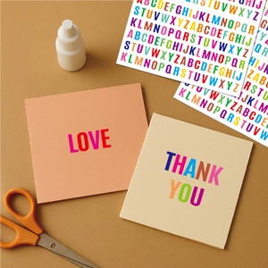Close-up of colorful waterproof alphabet stickers on DIY craft cards in orange and beige