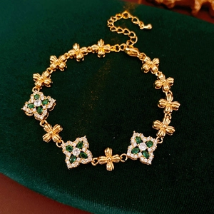 Detalle de pulsera vintage dorada con flores de circón verde sobre fondo terciopelo