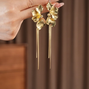 Details goldener Blumen-Ohrringe mit Quasten und funkelnden Steinen am Modell