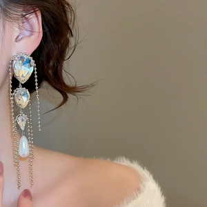 Close-up of elegant long tassel earrings with sparkling crystals and drop pearls on model