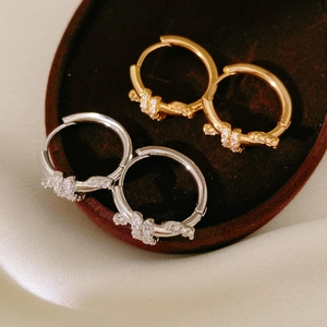 Macro shot of 18k gold and silver plated knotted hoop earrings with cubic zirconia