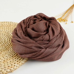 Detailed texture of brown cotton linen scarf folded into a rose shape on straw mat