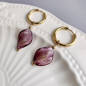 Detailed macro view of 18K gold hoop earrings with translucent purple floral petal charms