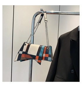 Detail of colorful geometric crossbody bag with silver chain on a metal hanger
