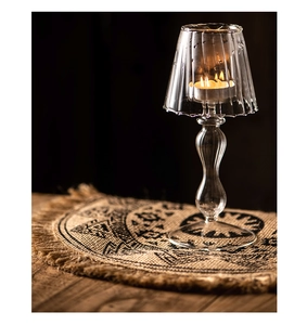 Detail of elegant glass candle holder with lampshade and burning candle on black background